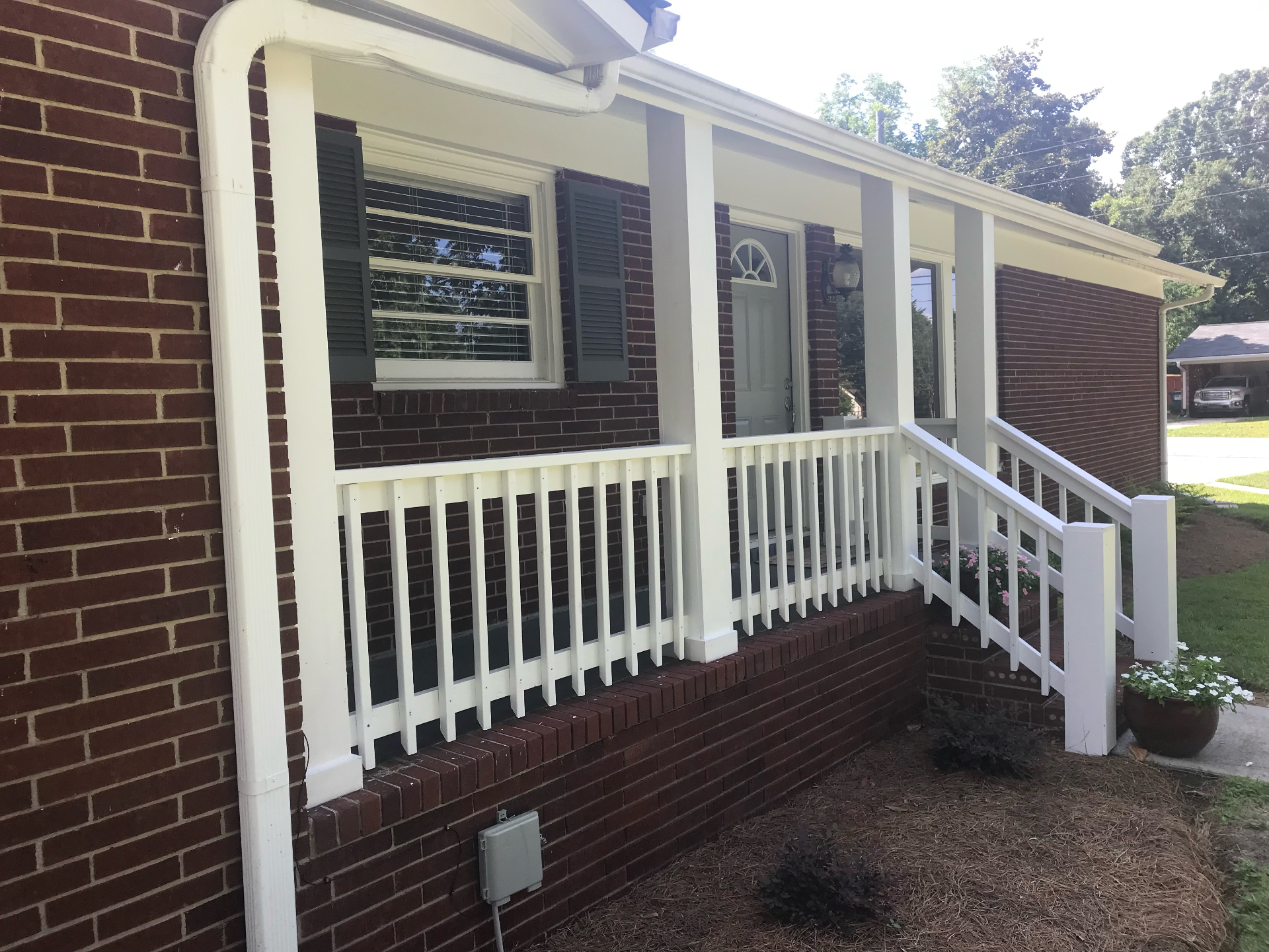 Freshly painted front porch and exterior trim on a brick home