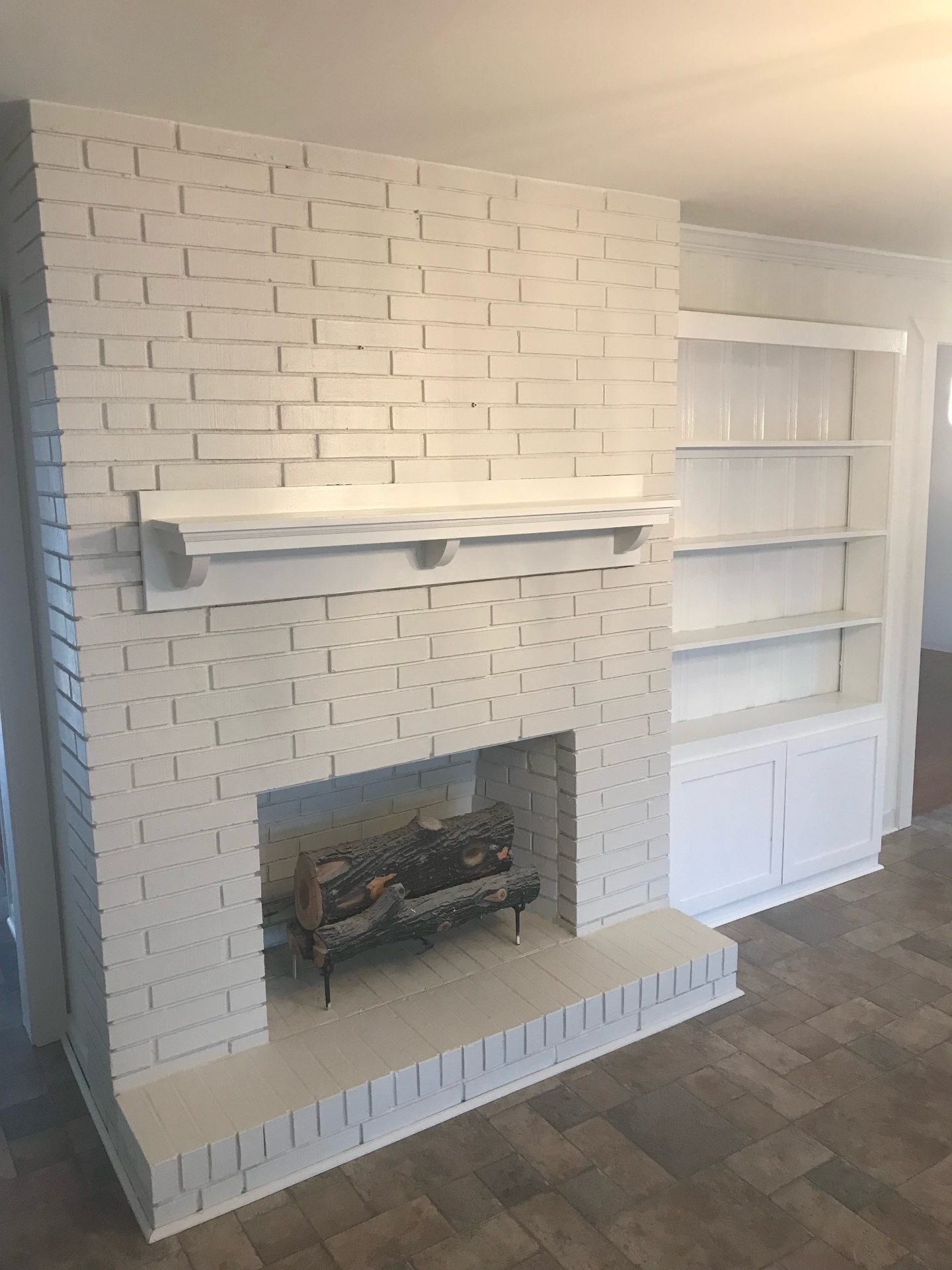 Freshly painted white brick fireplace and built-in shelves