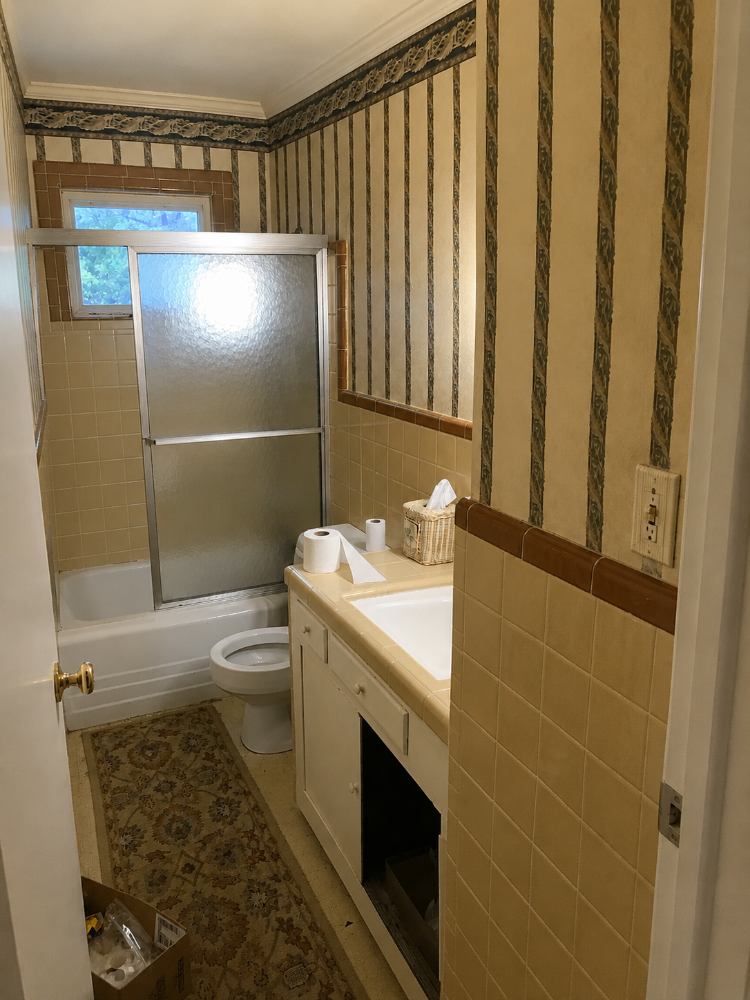 Bathroom with dated striped wallpaper and beige tile before remodel